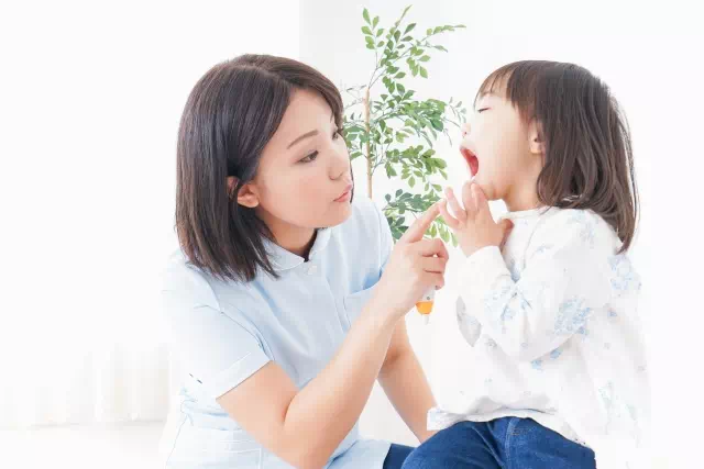 子供の歯をチェックする女性の画像